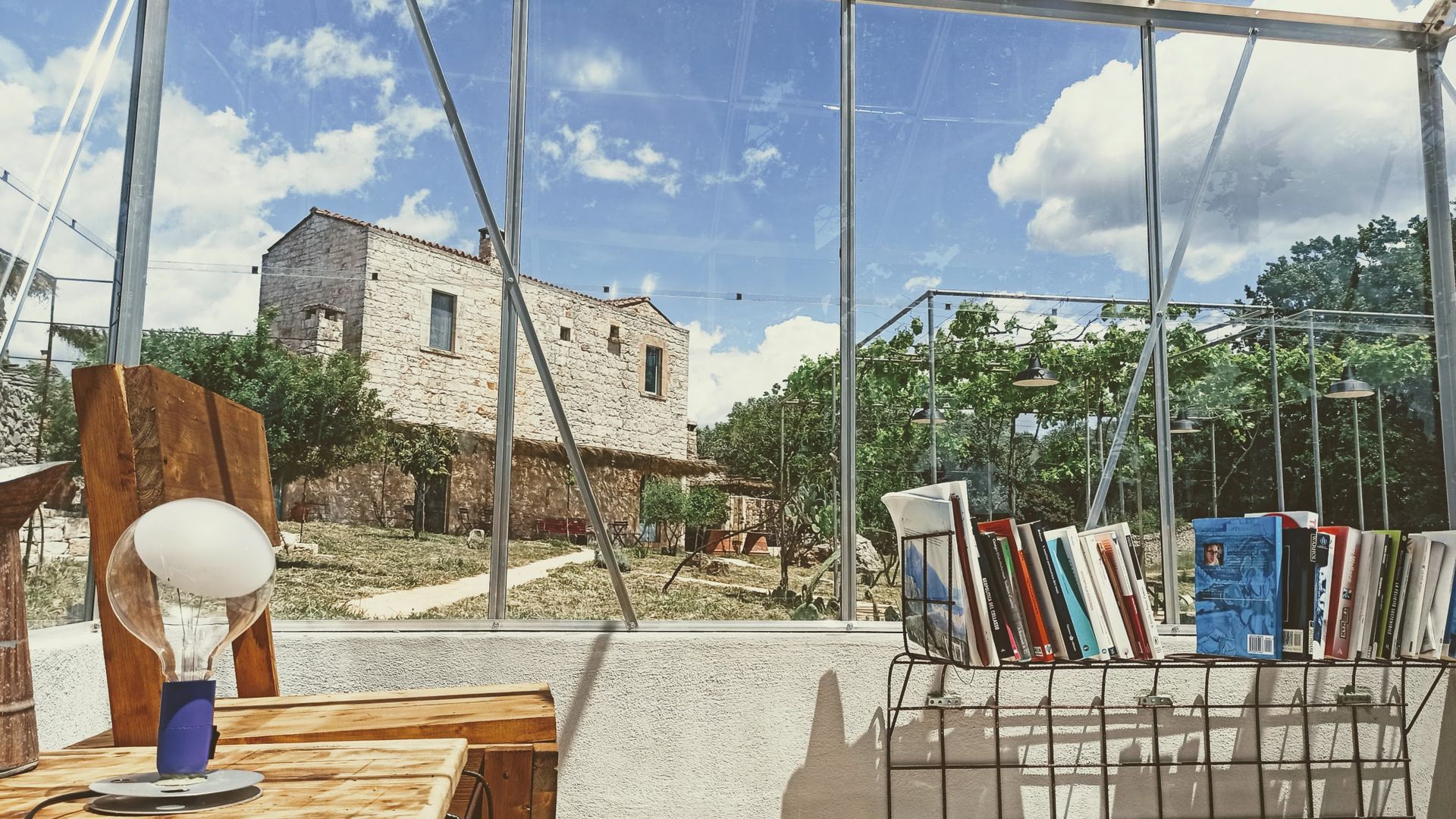 Una poltrona di legno, una lampada e i libri nella biblioserra